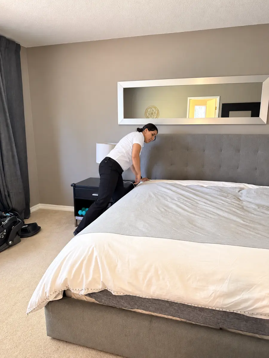Cleaner making a bed during a residential cleaning visit